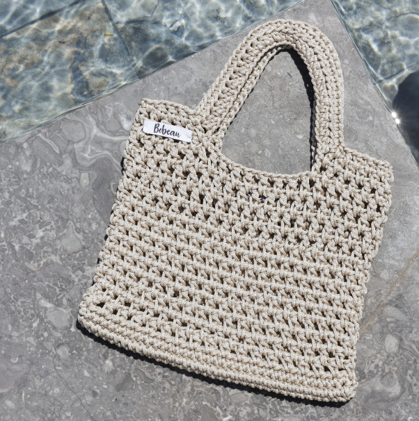 Sac beige artisanal de Bobeau Créations posé près d'une piscine, parfait pour une journée d'été